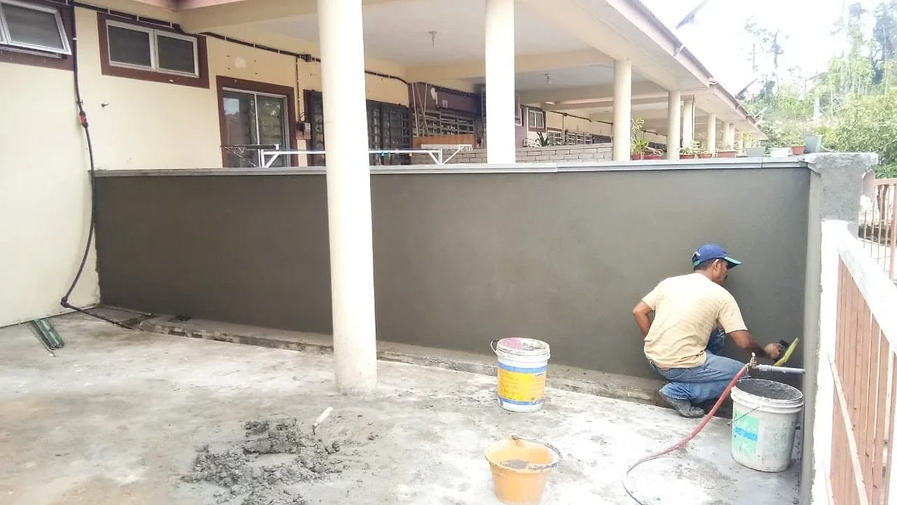Worker plastering the new brick fence wall around the porch