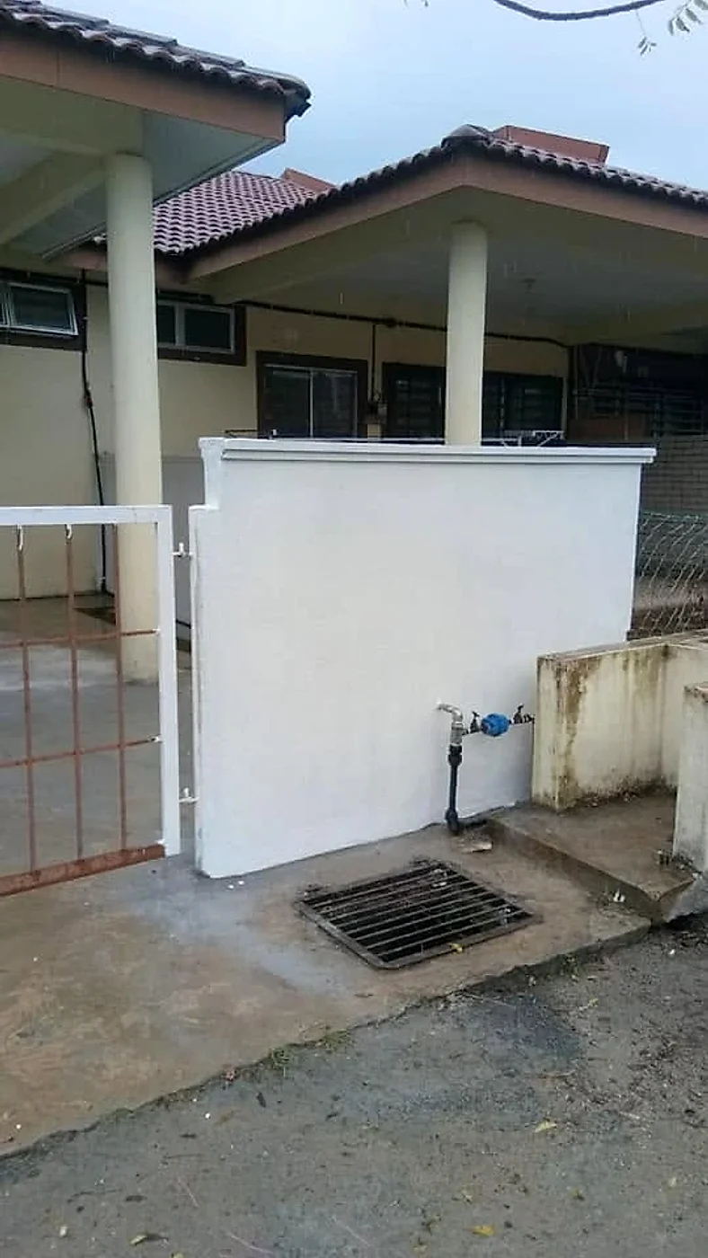 Finished white fence pillar beside the gate, with the water tap and drain