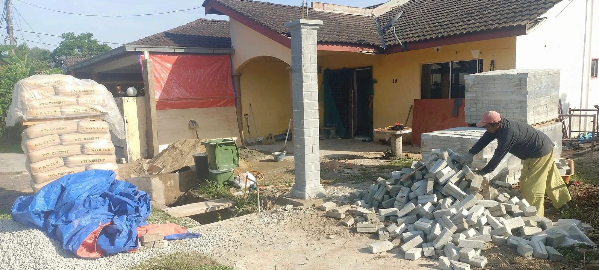 The house before work, with cement and bricks delivered and a new column cast