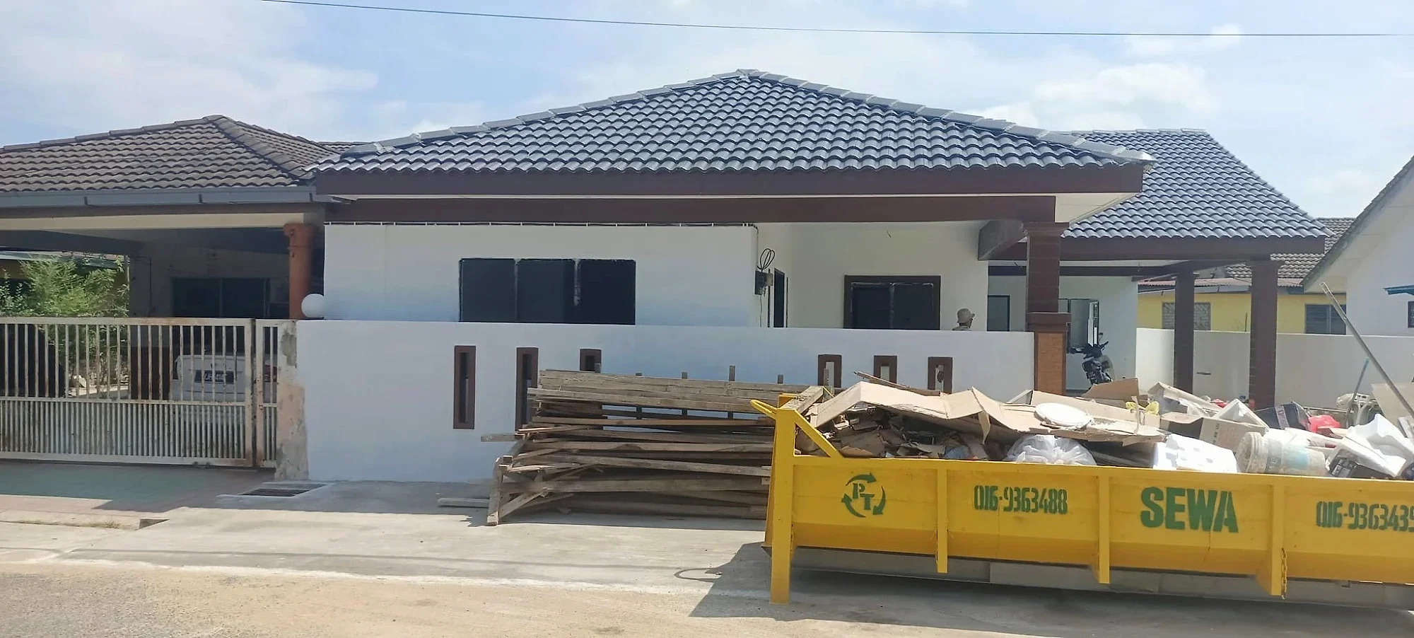 House painted white under its new tiled roof, with the site being cleared