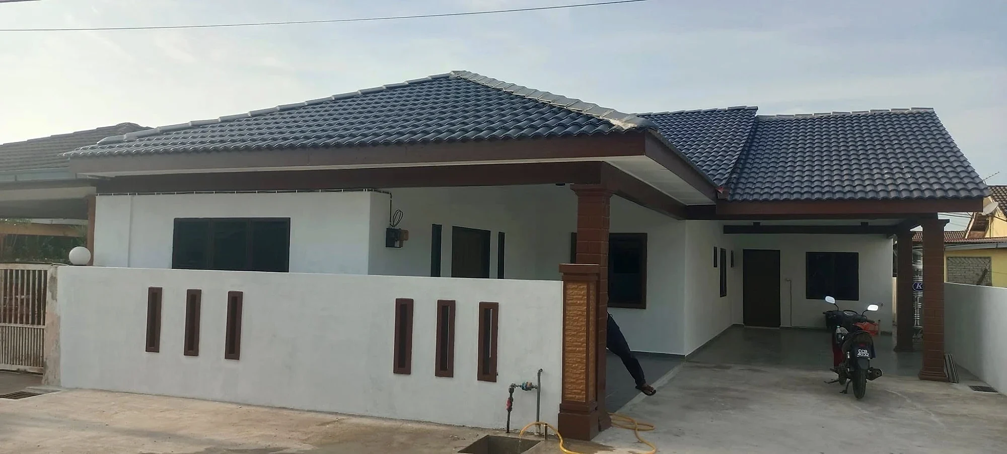 Finished extended house with a white front fence, brown columns and a dark tiled roof