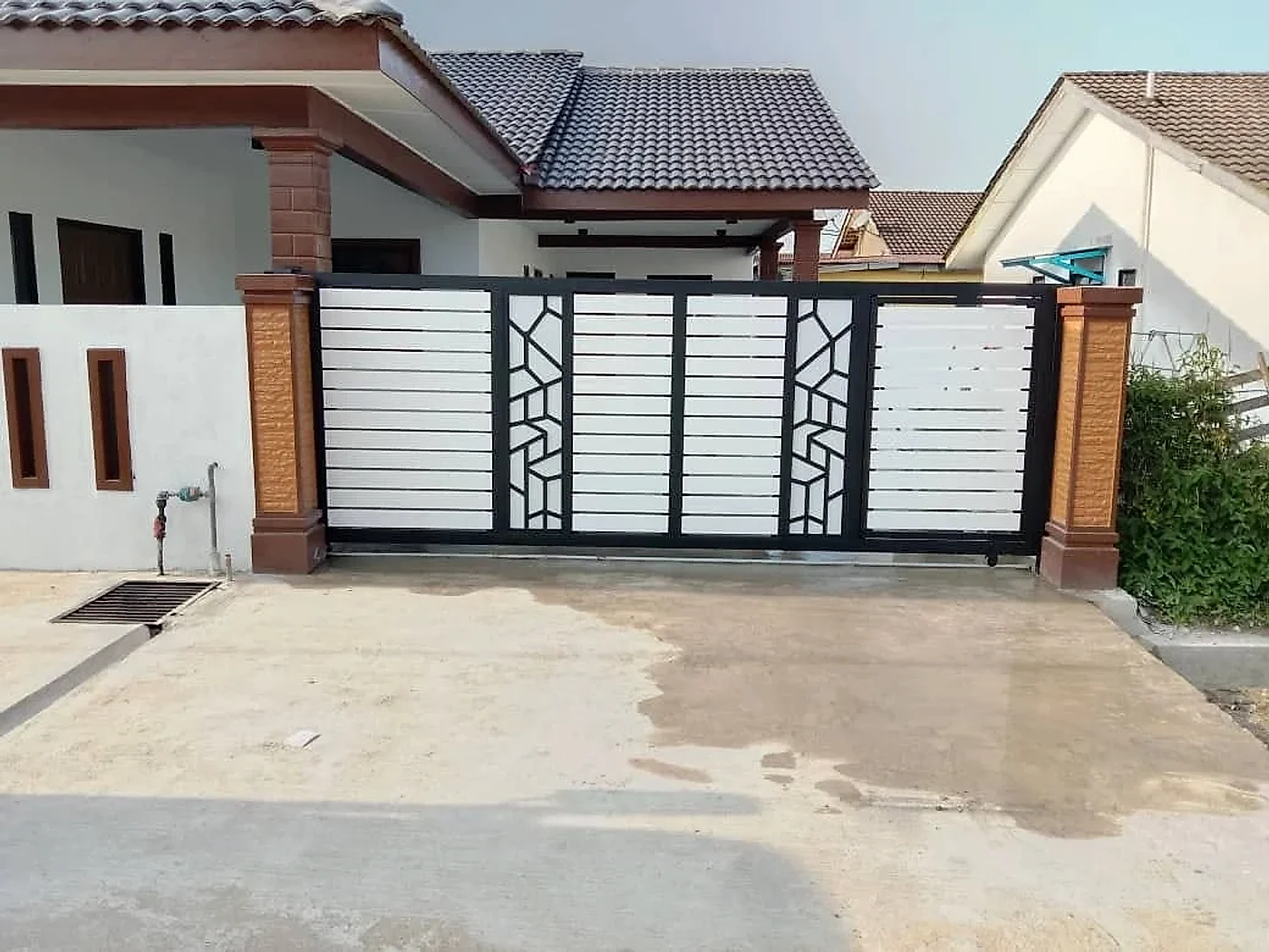 New black and white sliding gate between brown pillars