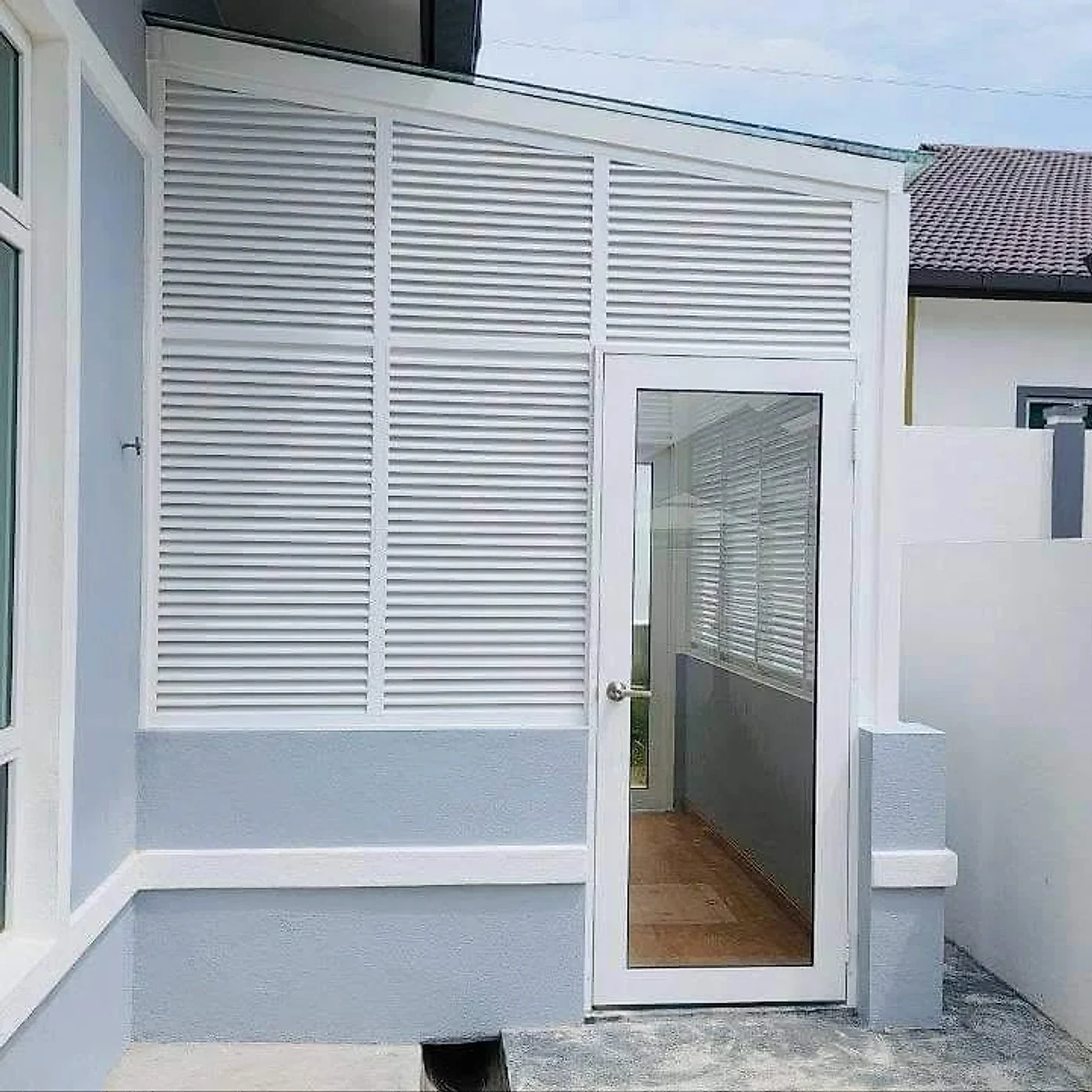 Finished side extension with white louvred aluminium panels and a glass door