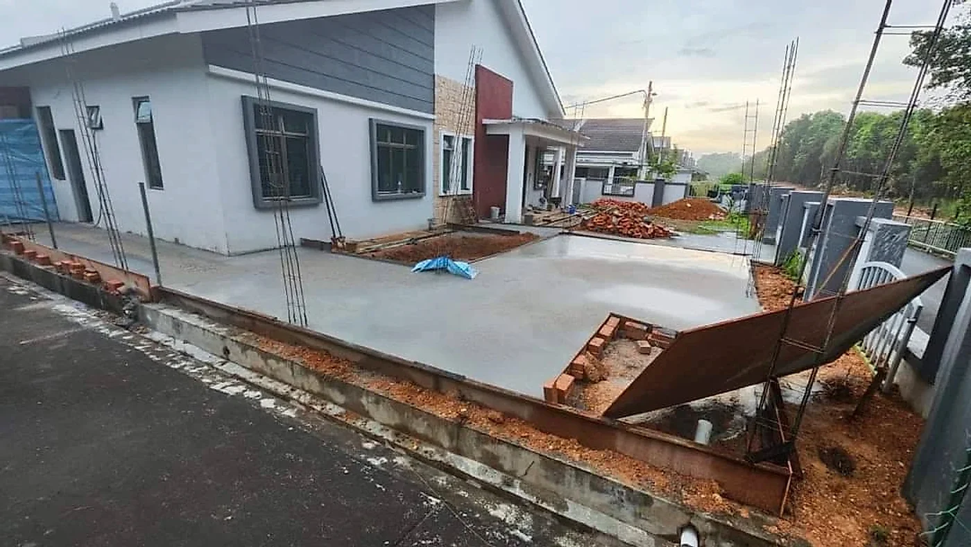 New concrete slab poured along the side of the house with starter bars for the columns