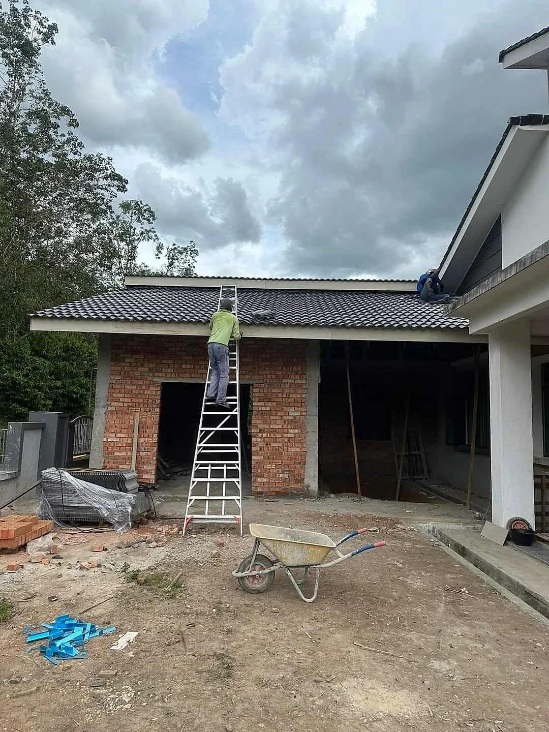 Roofers laying dark roof tiles on the new wing