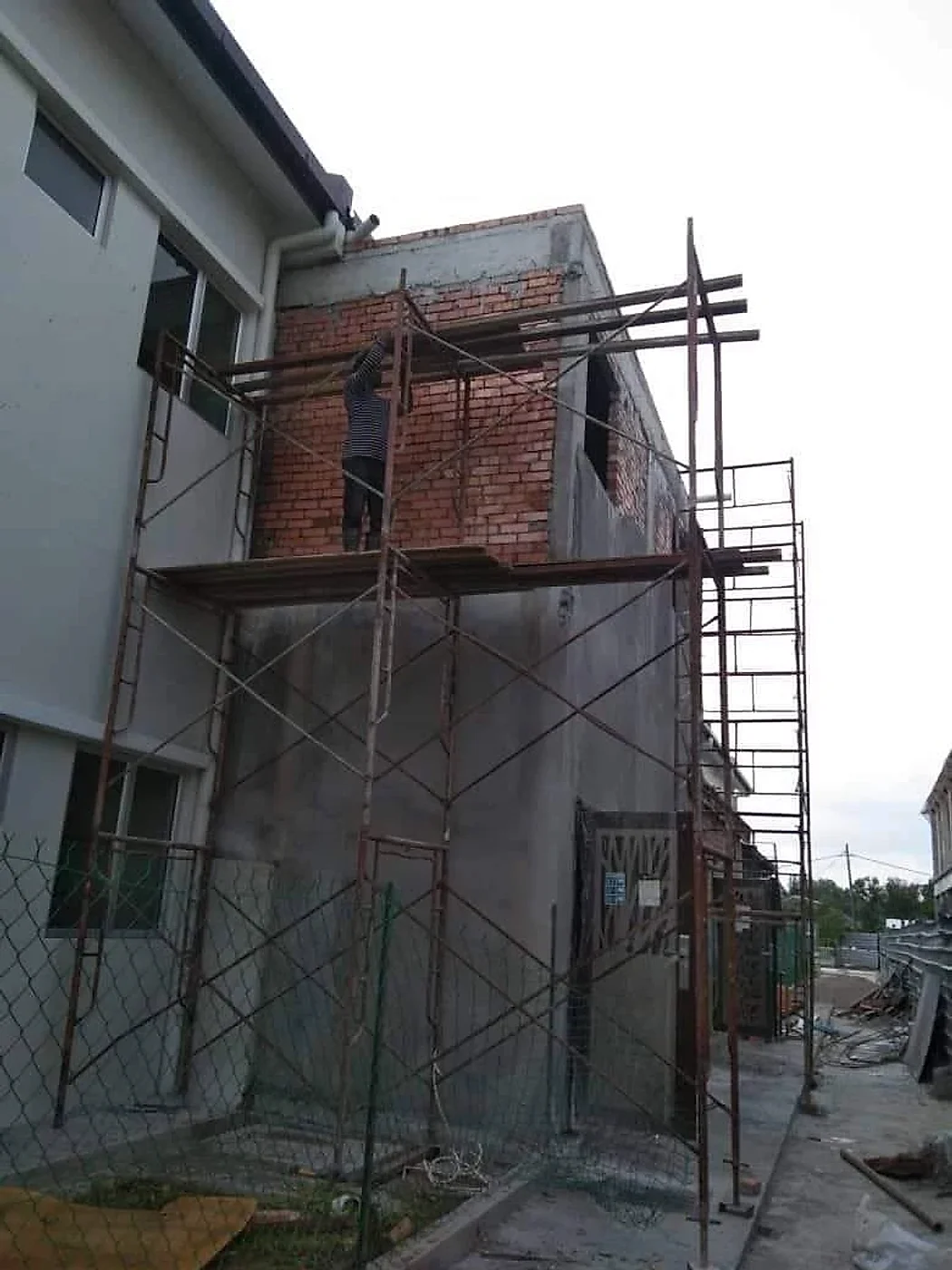 Bricklayer on scaffolding building the upper-floor walls of an extension