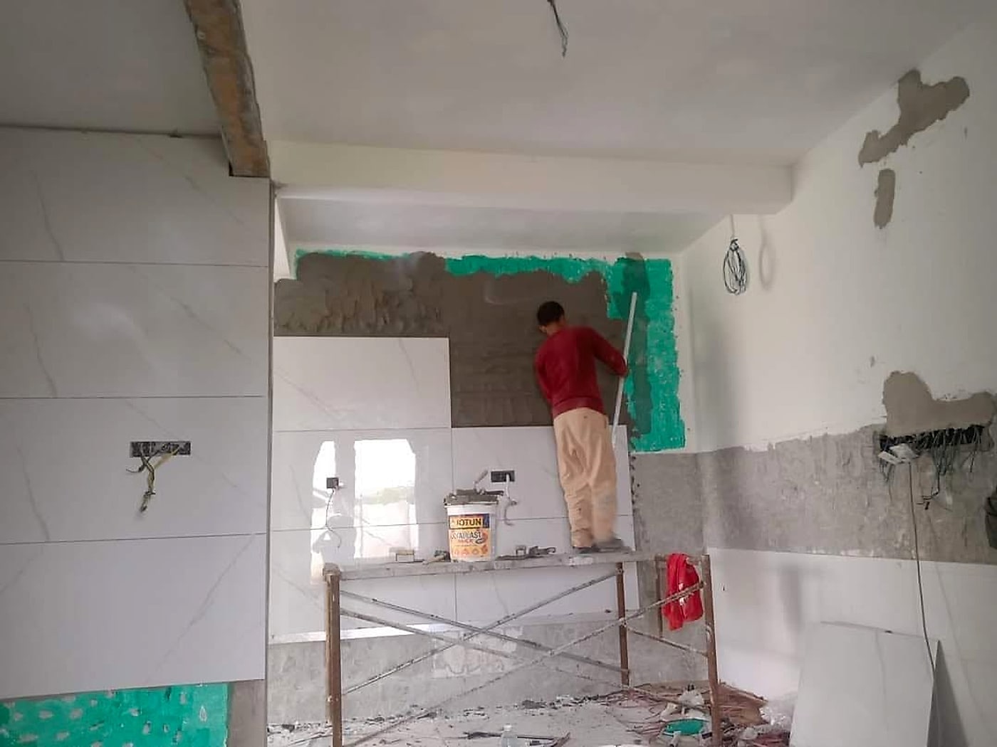 Tiler plastering a wall before fixing large marble-look tiles