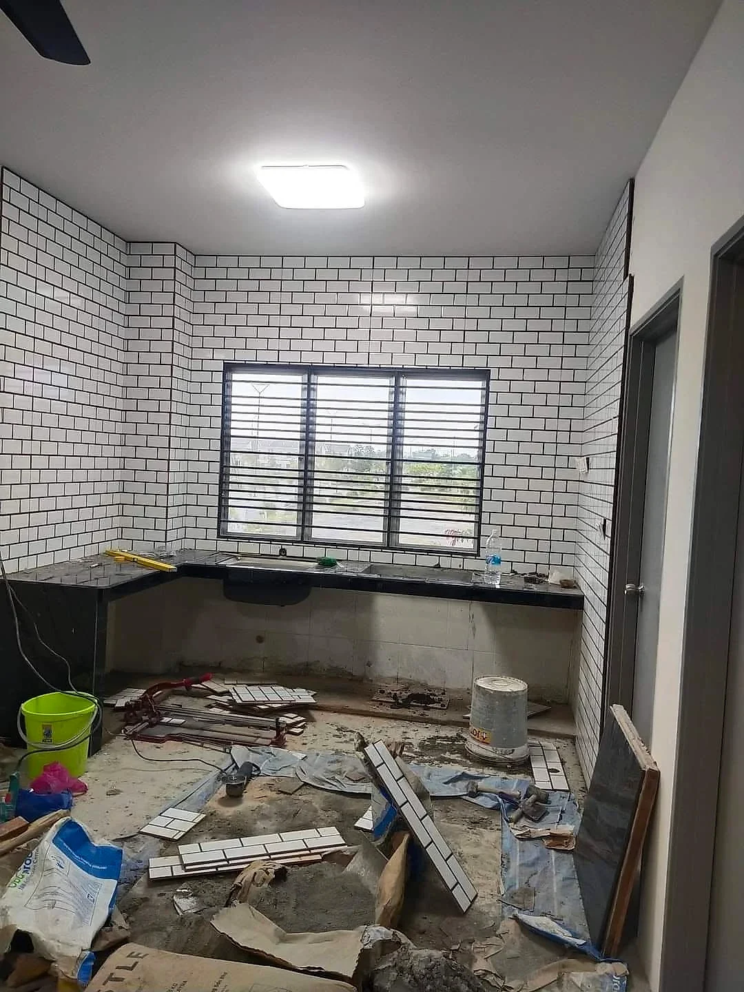 Kitchen walls finished in white subway tiles with black grout, counter in place
