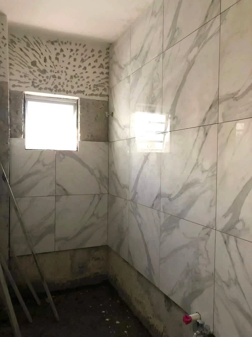 Large white marble-look tiles going up on the bathroom walls