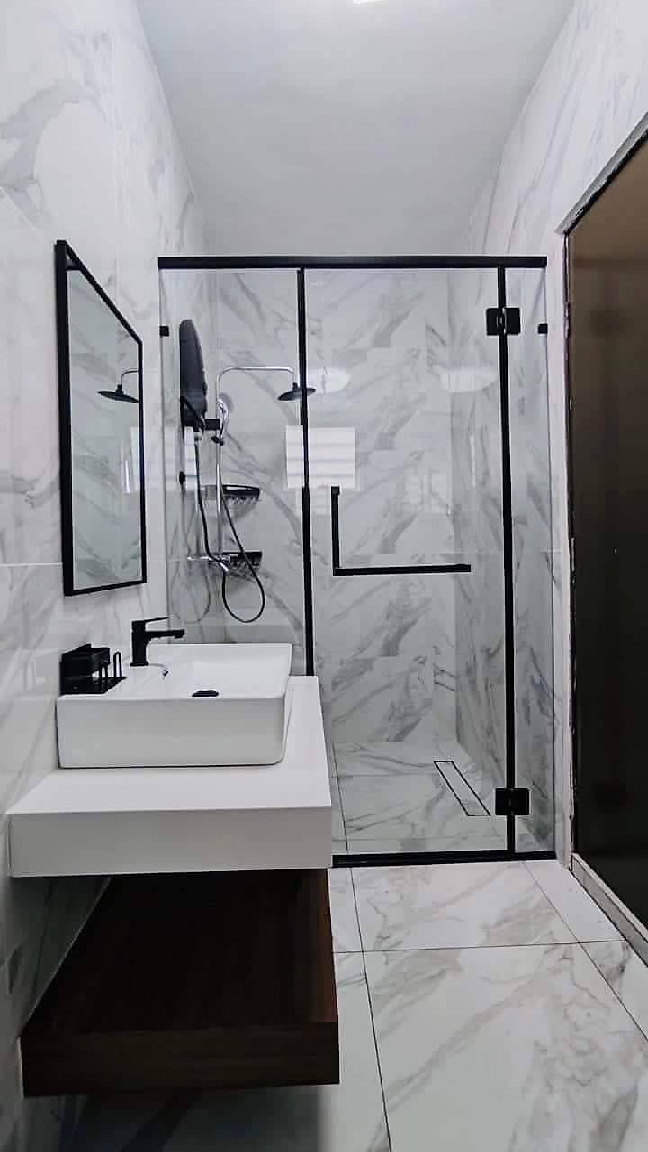 Glass shower screen with black frames and a rain shower
