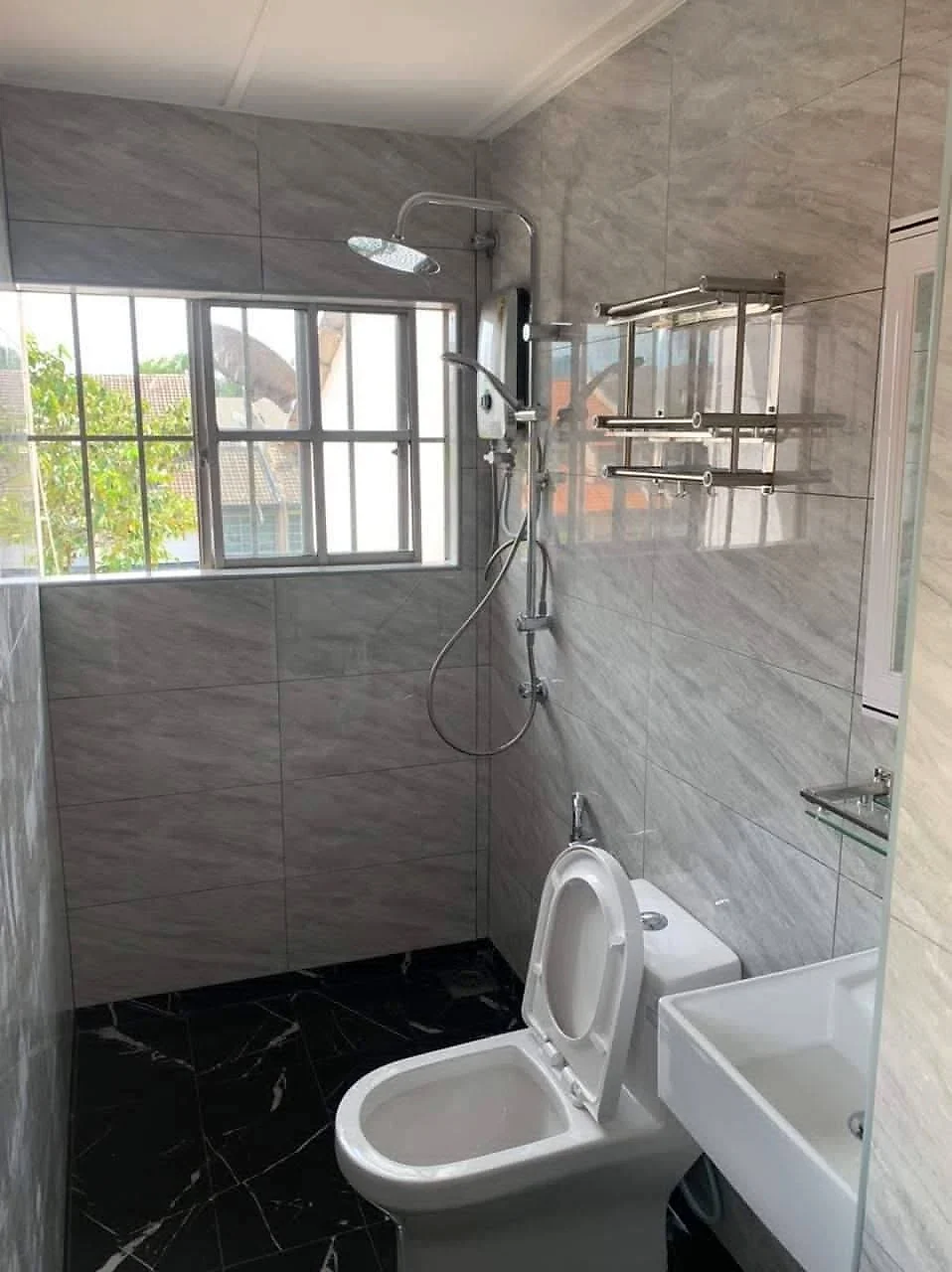 Finished bathroom with grey tiles, rain shower, water heater, toilet and basin