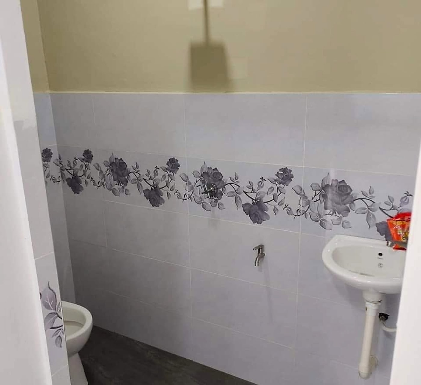 Finished toilet with floral border tiles and a dark wood-look floor