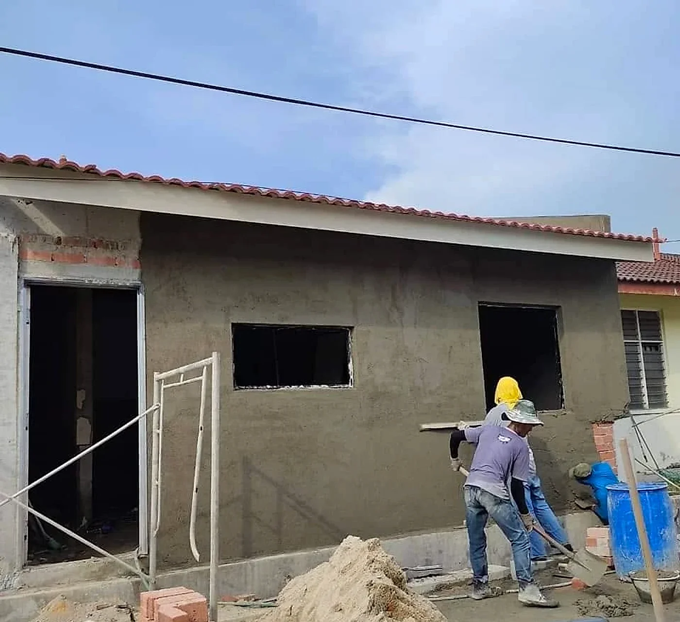 Workers plastering the outside walls of the new kitchen block under its tiled roof