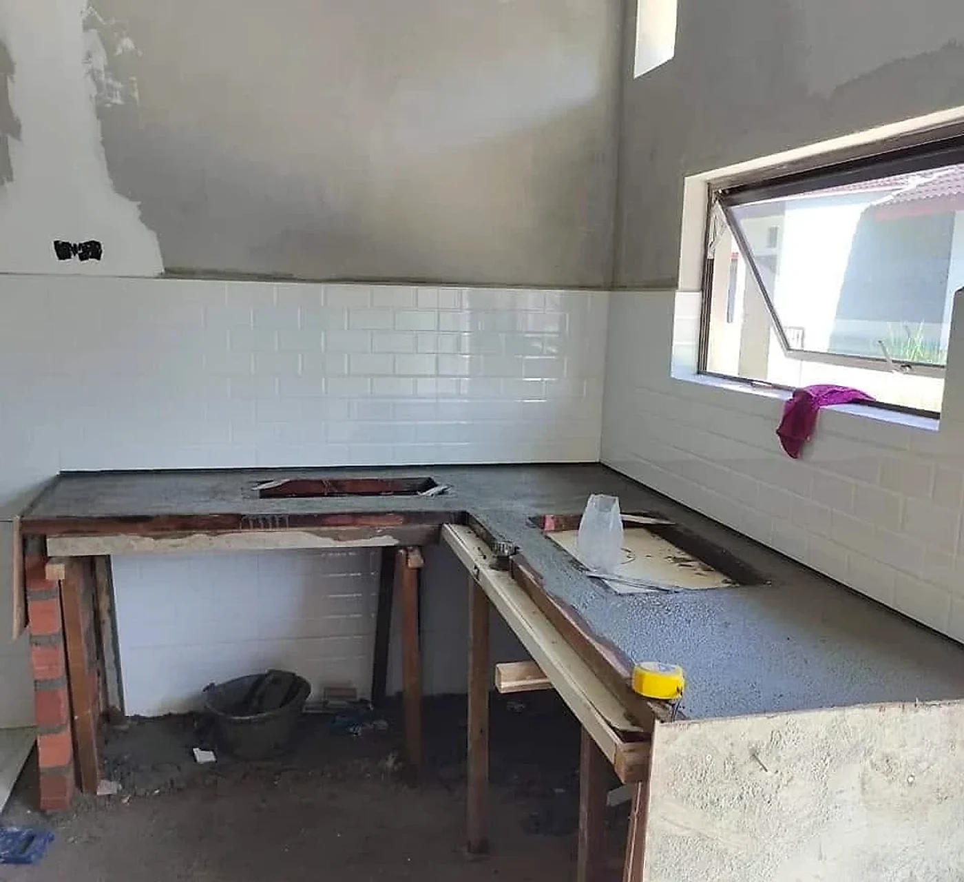 New concrete L-shaped counter cast with white subway tiles on the wall