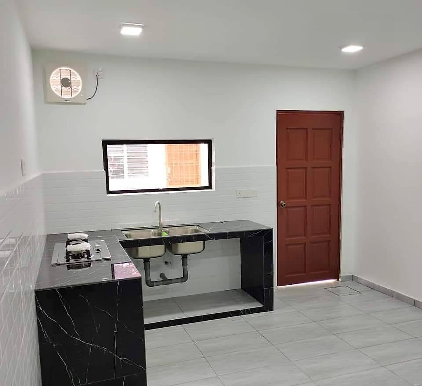 New wet kitchen with a black marble-look L-shaped counter, double sink and white wall tiles