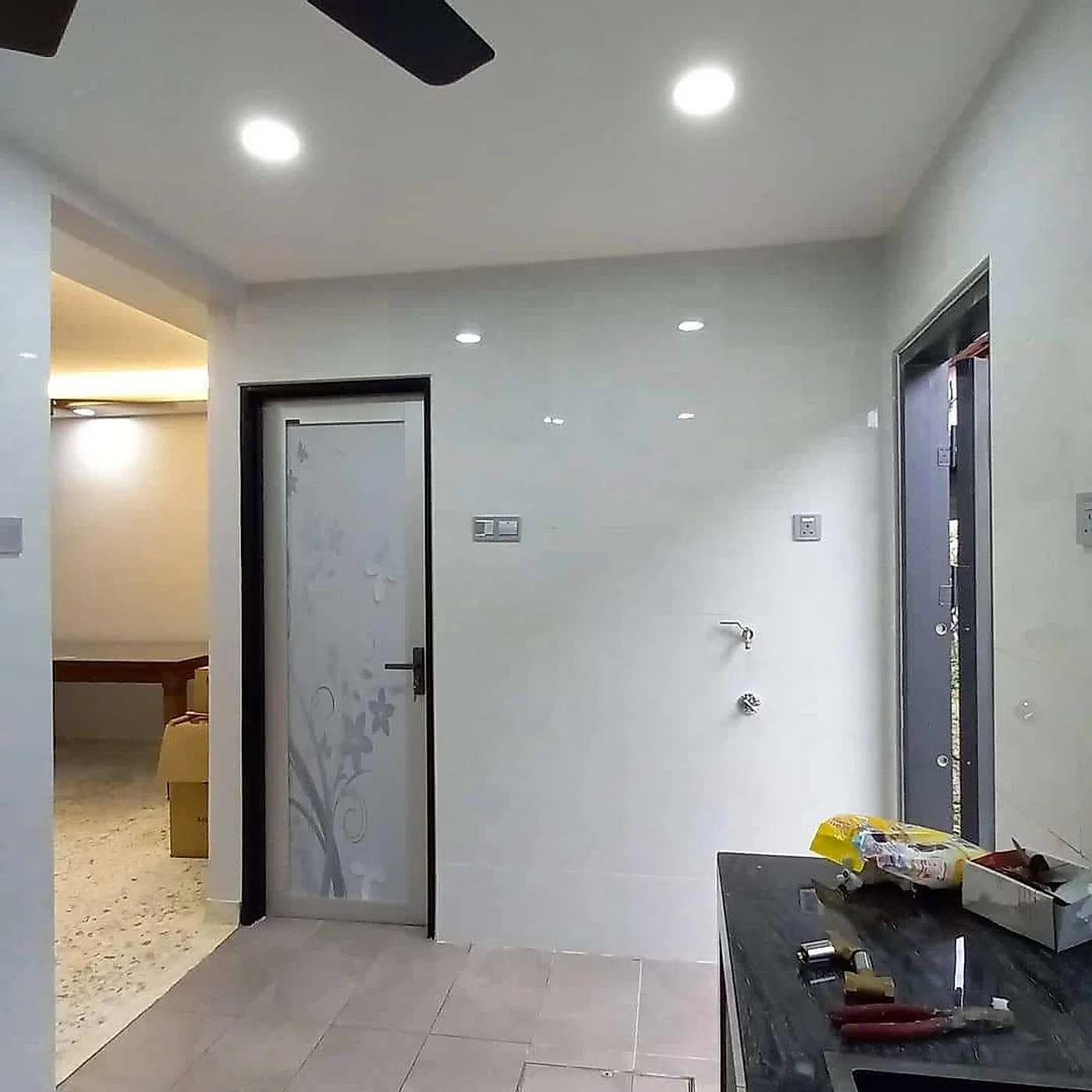 Finished kitchen with white wall tiles, a frosted glass door and downlights