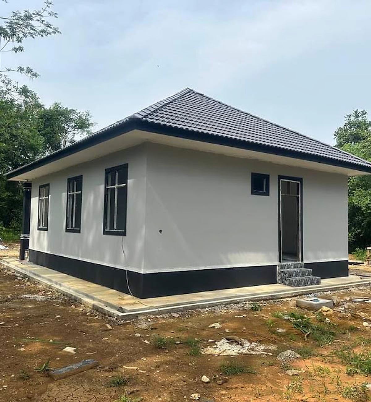 Hip-roof side of the bungalow with black window frames and plinth band