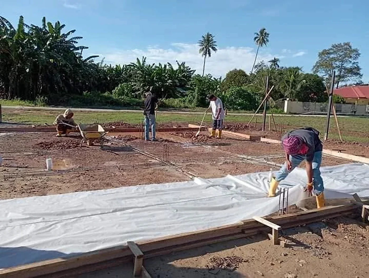 Crew laying the ground membrane and steel bars inside the slab formwork