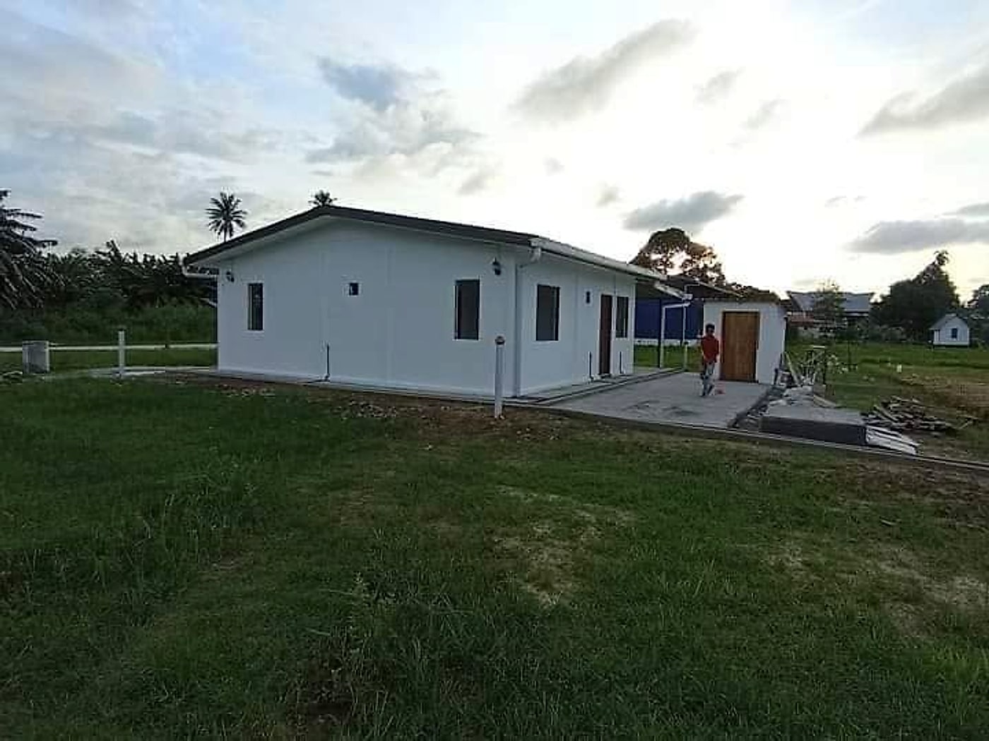 The finished single-storey house painted white on its plot