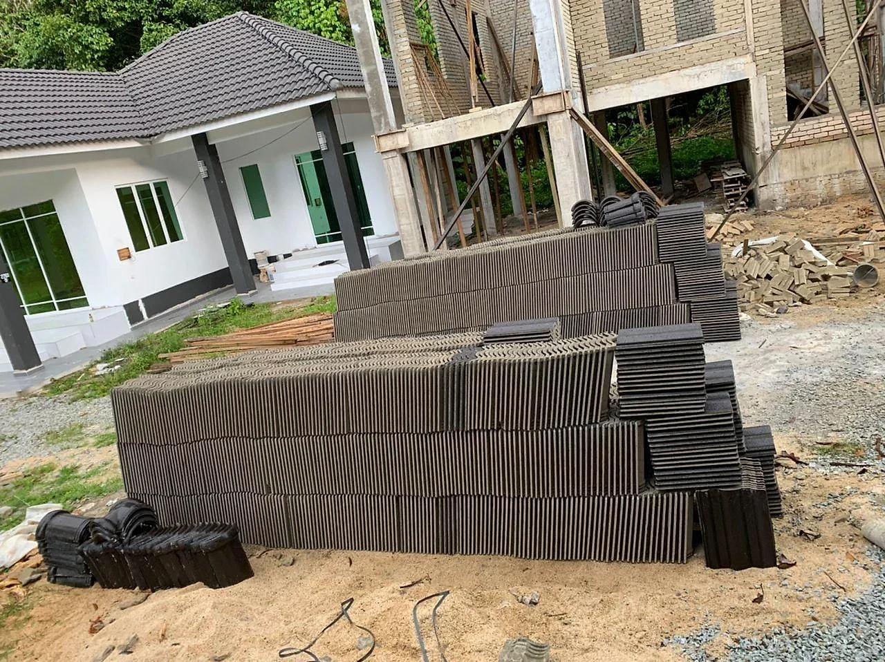 Stacks of dark roof tiles delivered beside the raised wing