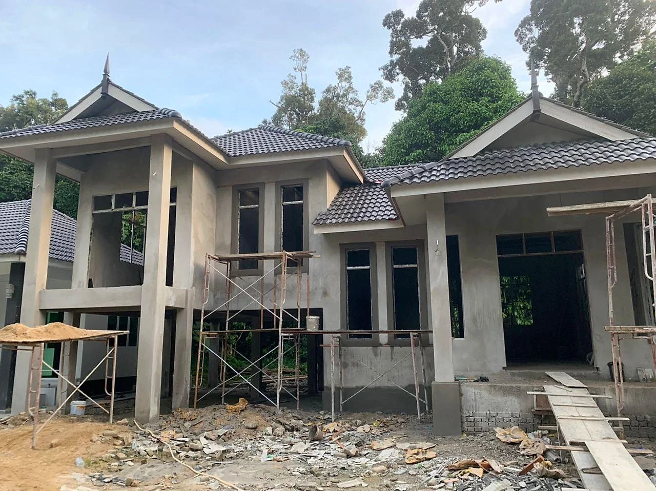 The house plastered with the dark tiled roof on, scaffolding in front
