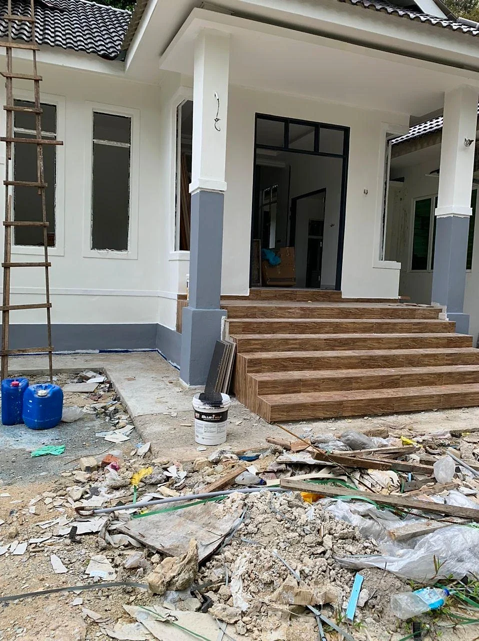 Porch steps tiled in wood-look tiles, site still being cleared