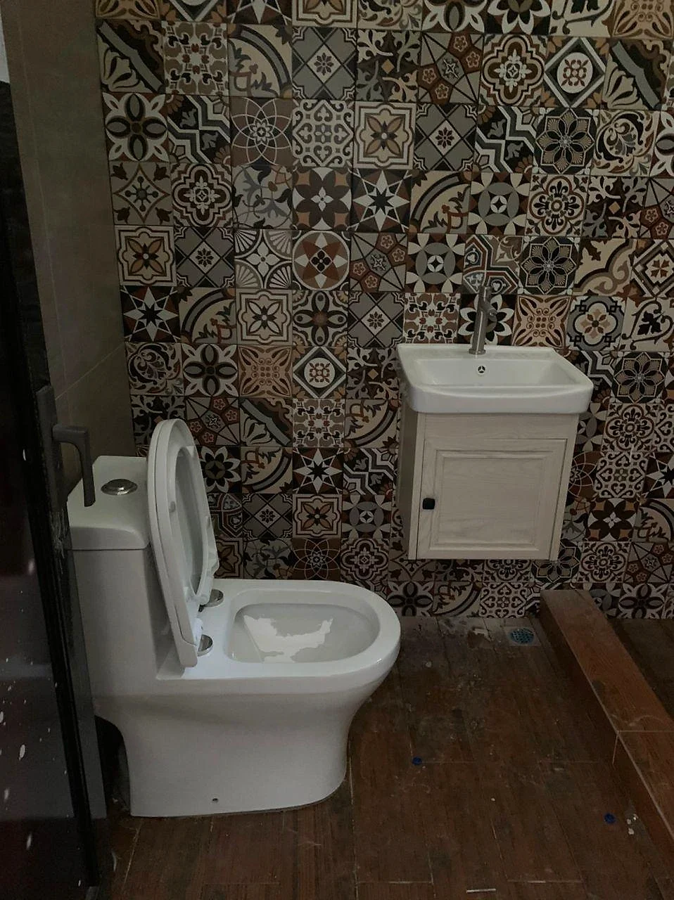 Bathroom with a patterned tile wall, toilet and vanity basin