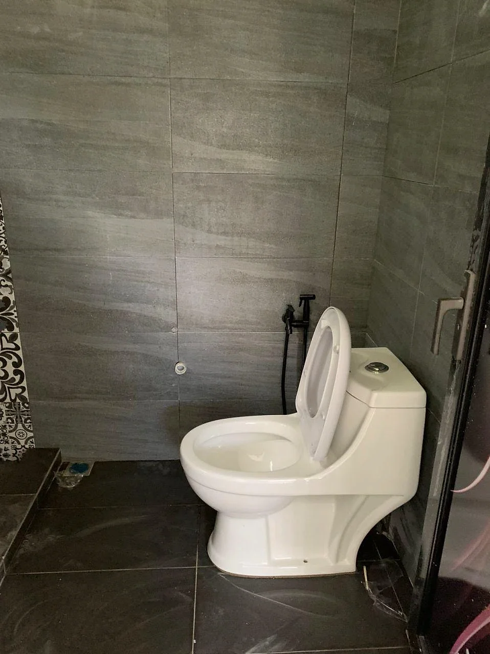 Bathroom in grey stone-look tiles with a new toilet and bidet spray