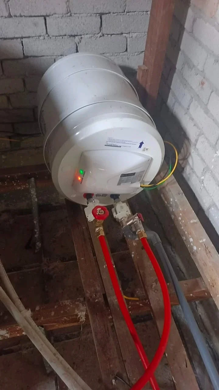 Storage water heater mounted in the roof space with new hot and cold pipes