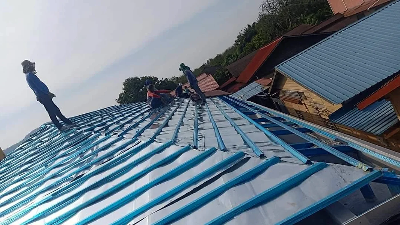 Roofers fixing steel roof battens over reflective foil insulation
