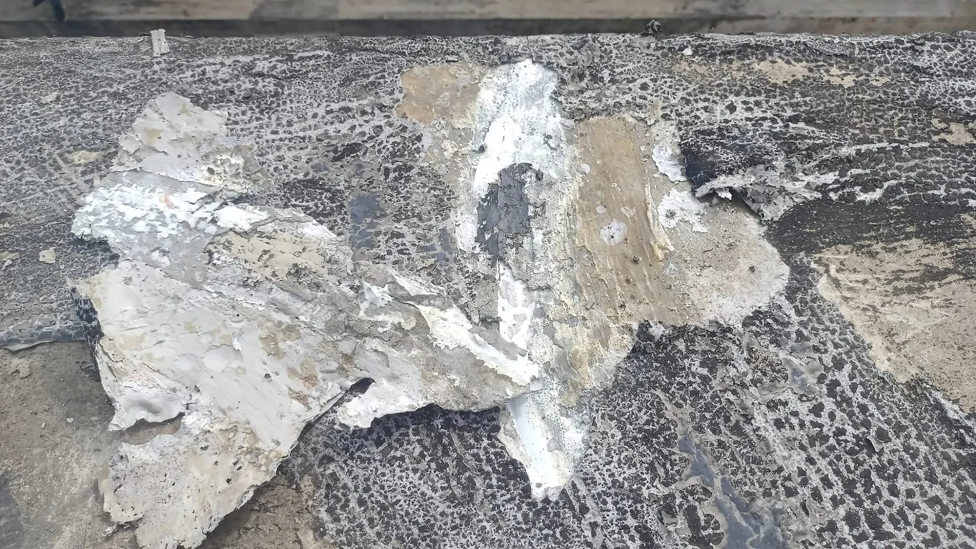 Old failed waterproofing peeling off the top of the roof slab