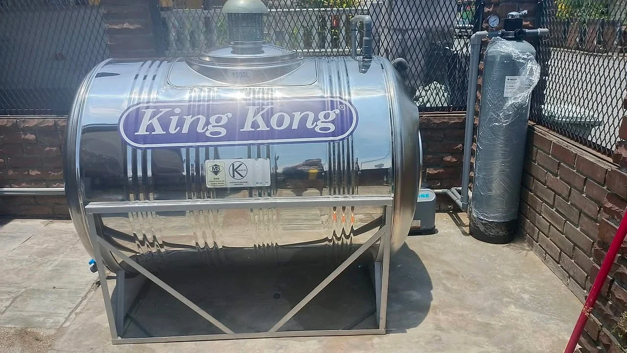 1000-litre stainless steel horizontal tank on its stand beside a water filter
