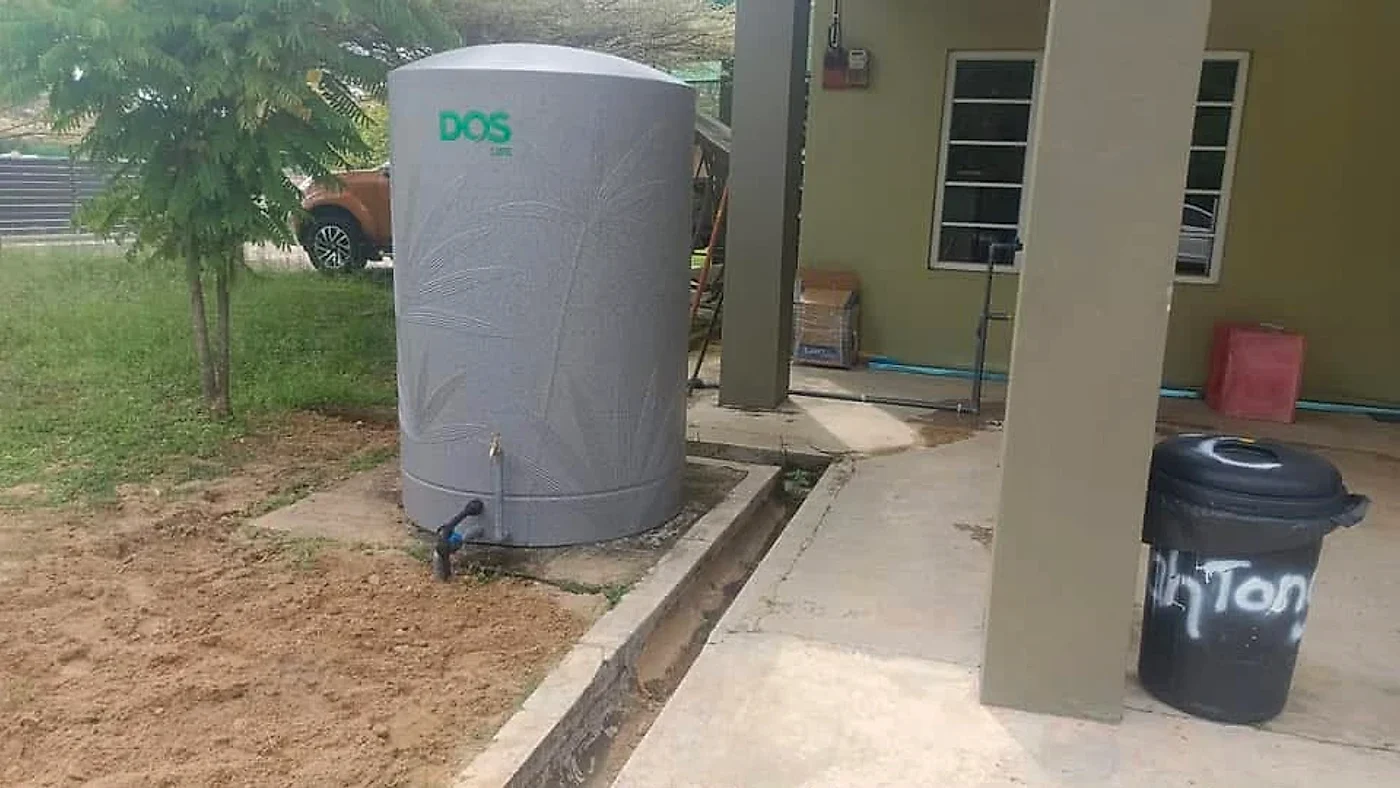 Grey polyethylene water tank installed on its new concrete base