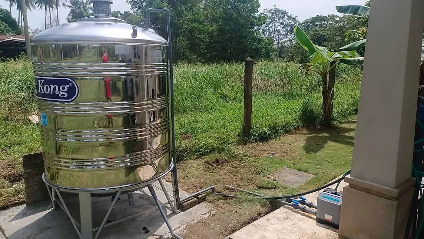 Stainless steel tank on a stand with a booster pump on the porch